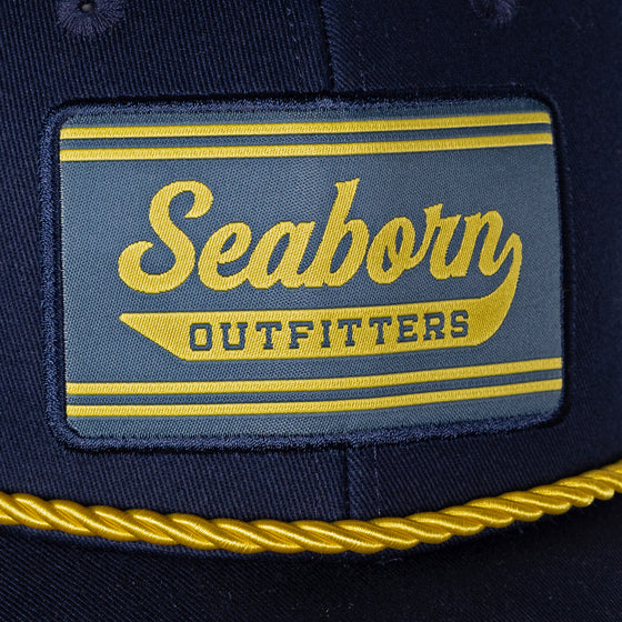 detail photo of front patch seaborn outfitters in yellow on navy background. yellow braided accent under patch above bill.
